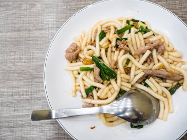 Domuz eti ve yeşil soğanlı kızarmış erişte.