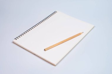 Beyaz masa arkaplanında tahta kalemle açık spiral boş defterin üst görünümü