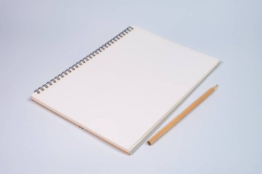 Beyaz masa arkaplanında tahta kalemle açık spiral boş defterin üst görünümü