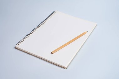 Beyaz masa arkaplanında tahta kalemle açık spiral boş defterin üst görünümü