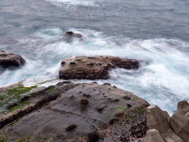 Güzel ipeksi su dalgaları ve deniz kıyısındaki kayalar