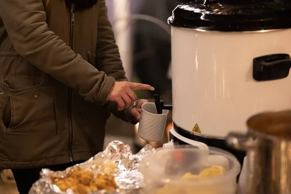 Woman pours mulled wine from a heat container — Stock Photo, Image