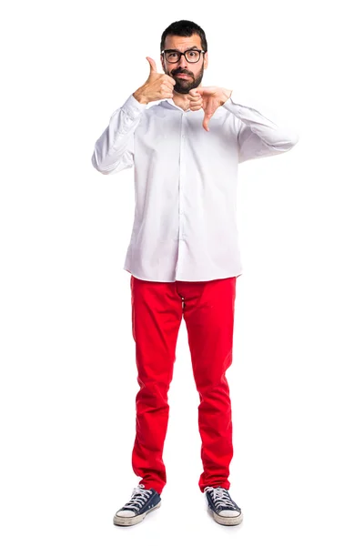 Hombre guapo con gafas haciendo buena-mala señal — Foto de Stock