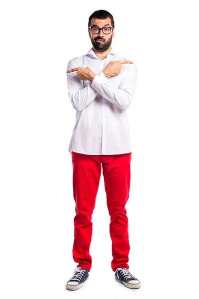 Hombre guapo con gafas apuntando a los laterales que tienen dudas — Foto de Stock