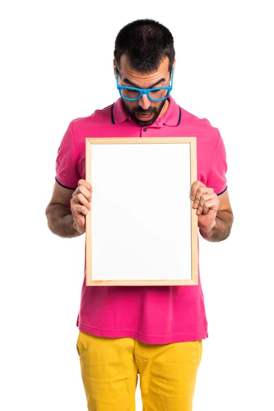 Homem com roupas coloridas segurando um cartaz vazio — Fotografia de Stock