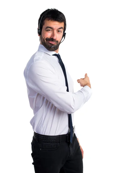 Young man with a headset pointing back — Stock Photo, Image