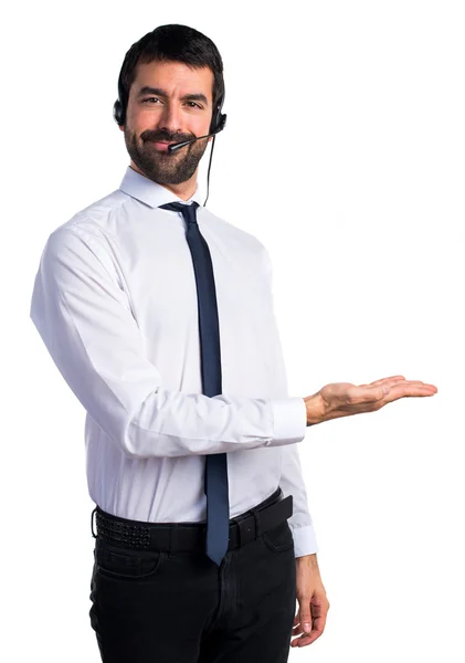 Joven con un auricular presentando algo — Foto de Stock