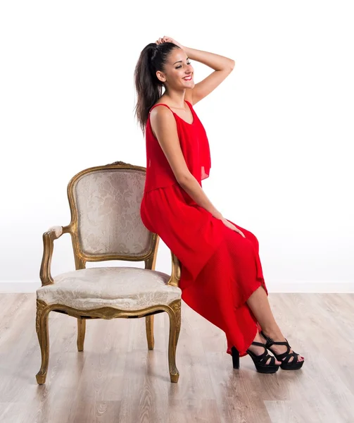 Linda chica con vestido rojo en sillón vintage — Foto de Stock