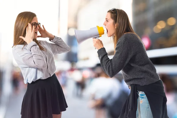 Girl shouting at her sister by megaphone — Stock Photo, Image