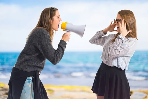 Girl shouting at her sister by megaphone — Stock Photo, Image