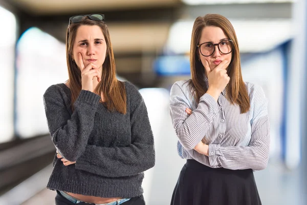 Hermanas gemelas pensando sobre fondo blanco —  Fotos de Stock