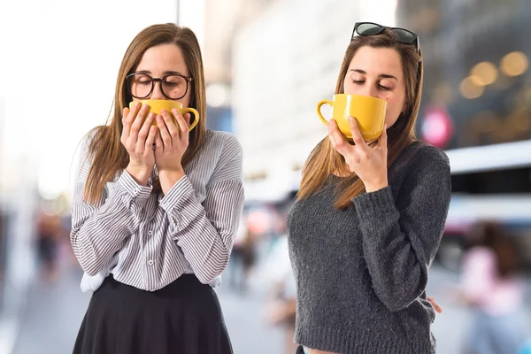 Tvillingsystrar som håller en kopp kaffe — Stockfoto