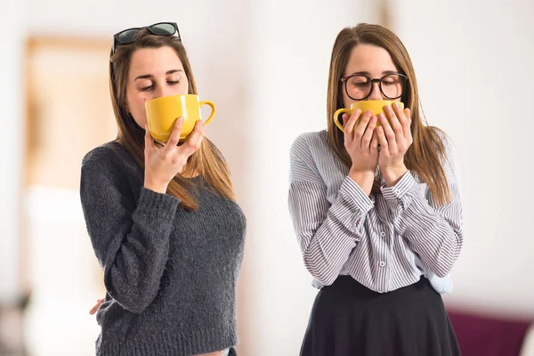 Tvillingsystrar som håller en kopp kaffe — Stockfoto