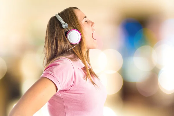 Joven chica rubia escuchando música sobre fondo blanco —  Fotos de Stock