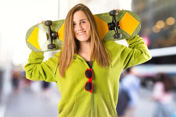 Menina loira com skate sobre fundo branco — Fotografia de Stock