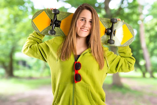 Ragazza bionda con skate su sfondo bianco — Foto Stock