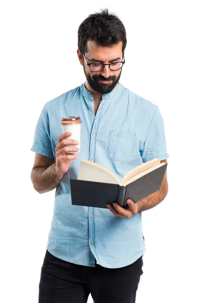 Bello uomo con occhiali blu libro di lettura e bere caffè — Foto Stock