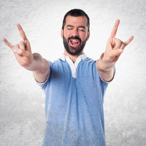 Hombre con camisa azul haciendo gesto de cuerno —  Fotos de Stock