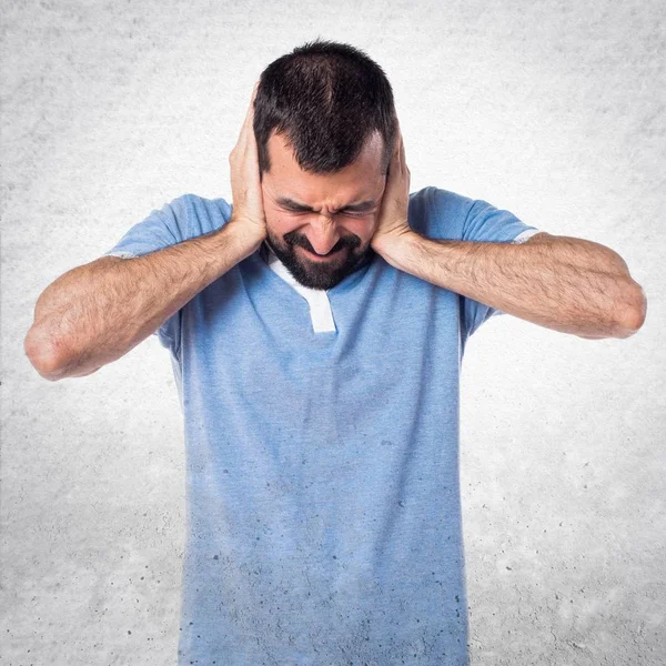 Man with blue shirt covering his ears — Stock Photo, Image