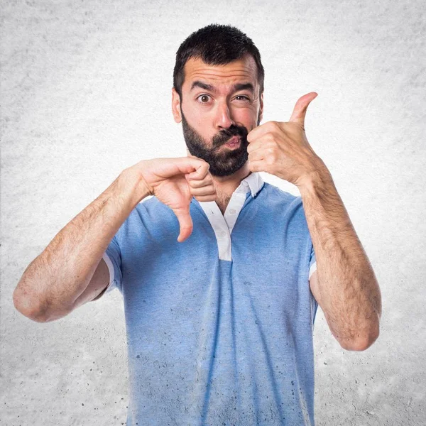 Man med blå skjorta att göra bra-dåligt tecken — Stockfoto