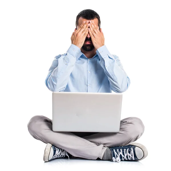Man met laptop die betrekking hebben op zijn ogen — Stockfoto