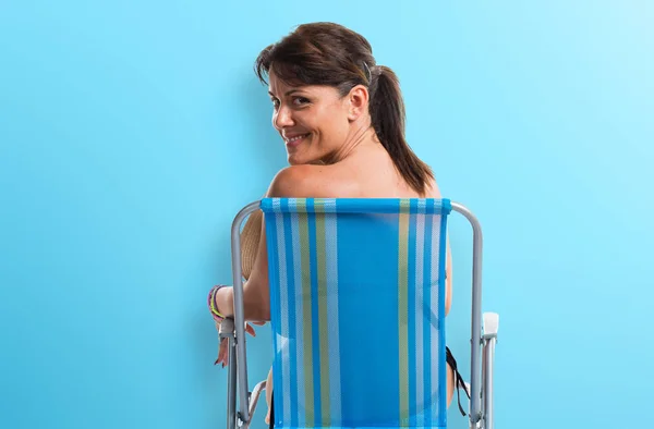 Kvinnan i blå bikini sitter i en stol — Stockfoto