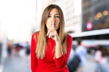 Genç kız izole edilmiş beyaz arka planda sessizlik jesti yapıyor. 