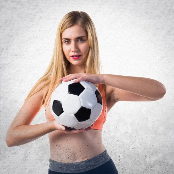 Όμορφη ξανθιά κοπέλα που κρατά μια μπάλα ποδοσφαίρου — Φωτογραφία Αρχείου