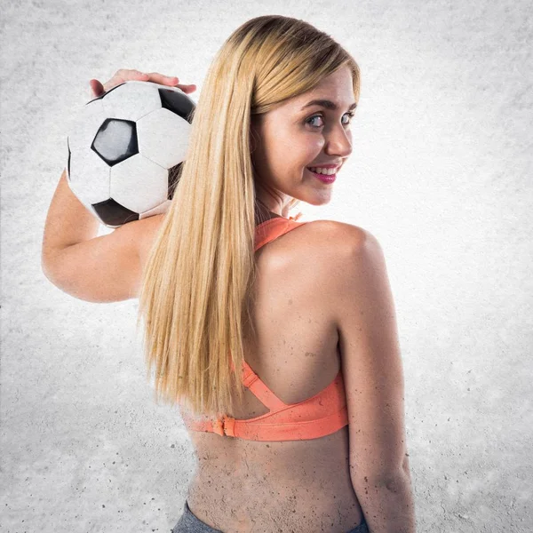 Όμορφη ξανθιά κοπέλα που κρατά μια μπάλα ποδοσφαίρου — Φωτογραφία Αρχείου