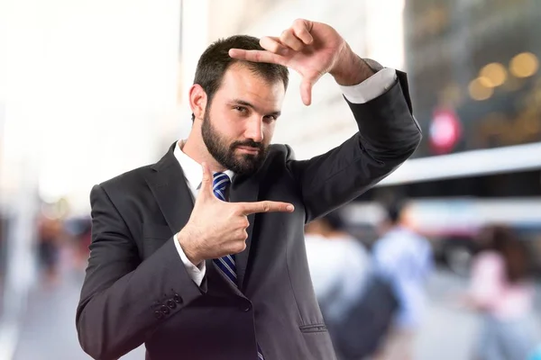 Junger Geschäftsmann macht ein Rahmenschild vor weißem Hintergrund — Stockfoto