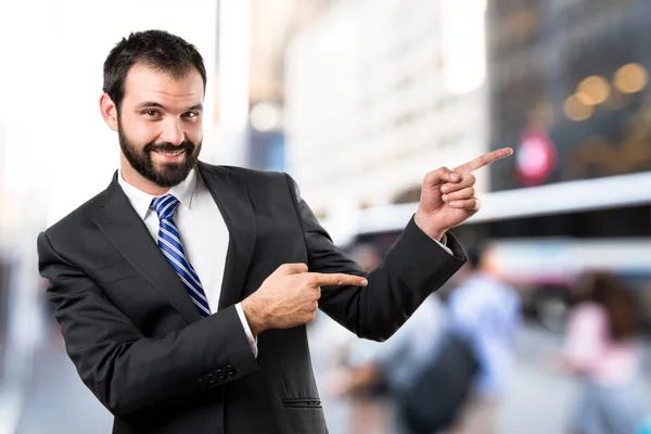 Businessman pointing to the side over white background