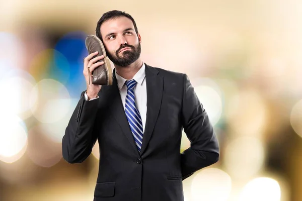 Junger Geschäftsmann im Gespräch mit seinem Schuh vor weißem Hintergrund — Stockfoto