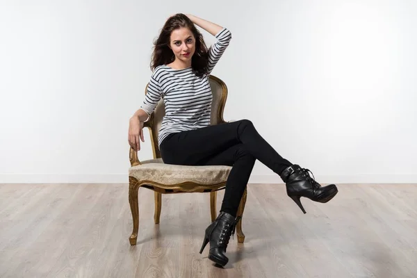 Beautiful model woman posing in studio with a vintage armchair — Stock Photo, Image