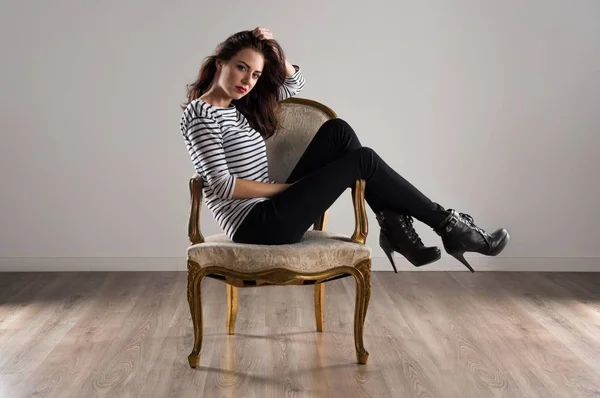 Piękny model kobieta stwarzających w studio z rocznika fotel — Zdjęcie stockowe
