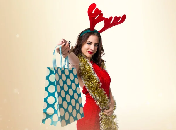 Mulher bonita com saco de natal e chifres de rena — Fotografia de Stock