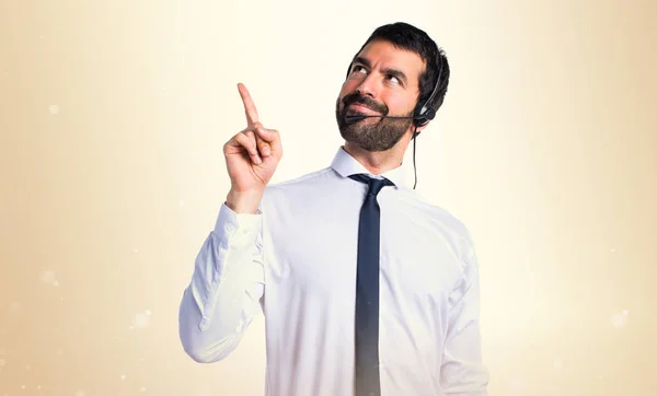 Joven con un auricular apuntando hacia arriba — Foto de Stock