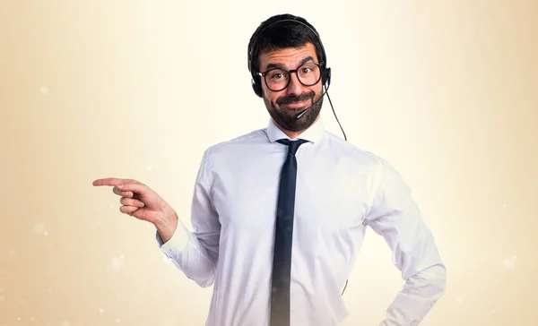 Jovem com um fone de ouvido apontando para a lateral — Fotografia de Stock