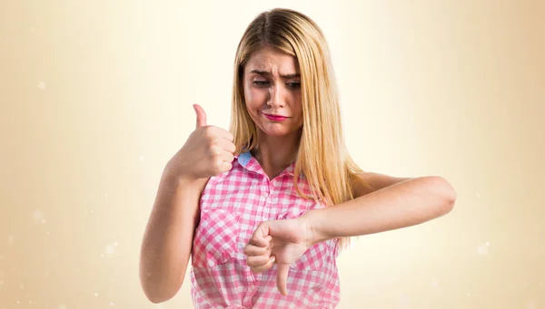 Chica rubia haciendo buena-mala señal — Foto de Stock