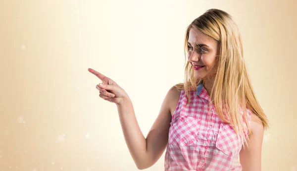 Blonde girl pointing to the lateral — Stock Photo, Image