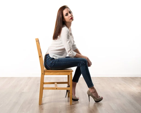 スタジオの椅子の上でポーズをとってきれいなモデルを若い女性 — ストック写真