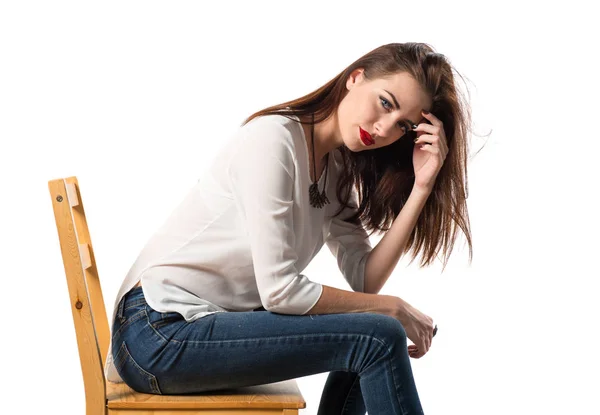Mladý hezký model žena pózuje v studio na židli — Stock fotografie