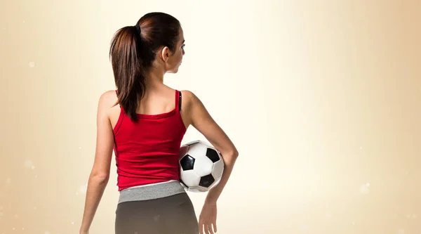 Hübsche Sportlerin in der Hand eines Fußballs — Stockfoto