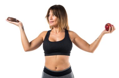 Bir elinde bir elma ve çörek diğer elinde tutan spor kadın