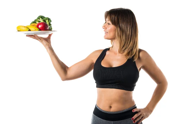 Donna sportiva che detiene frutta e verdura — Foto Stock