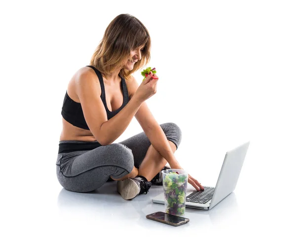 Nutritionist working with her laptop while eating a salad — Stock Photo, Image