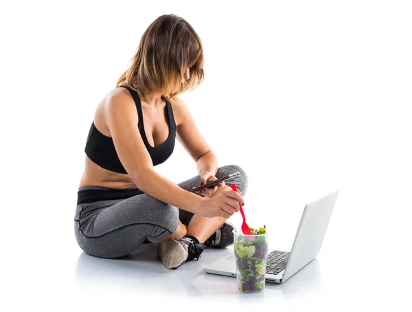 Nutritionist working with her laptop while eating a salad — Stock Photo, Image