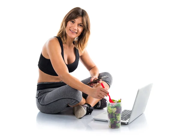 Sport woman working with her laptop while eating a salad — Stock Photo, Image