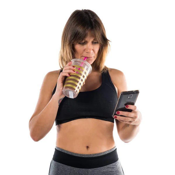 Sport woman with her mobile and drinking a sport drink — Stock Photo, Image