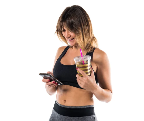 体育女人与她的手机和她运动饮料 — 图库照片