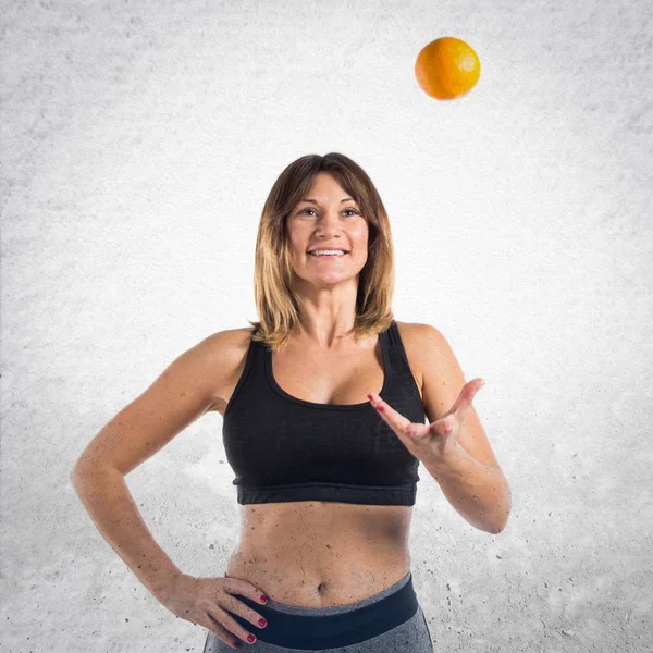 Sport woman playing with an orange — Stock Photo, Image